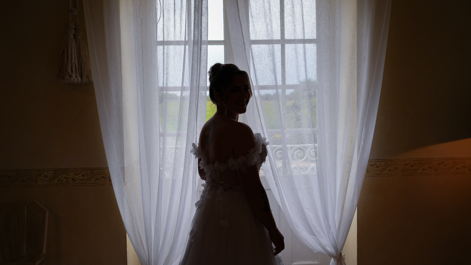Préparatifs de la mariée en contre-jour devant une fenêtre